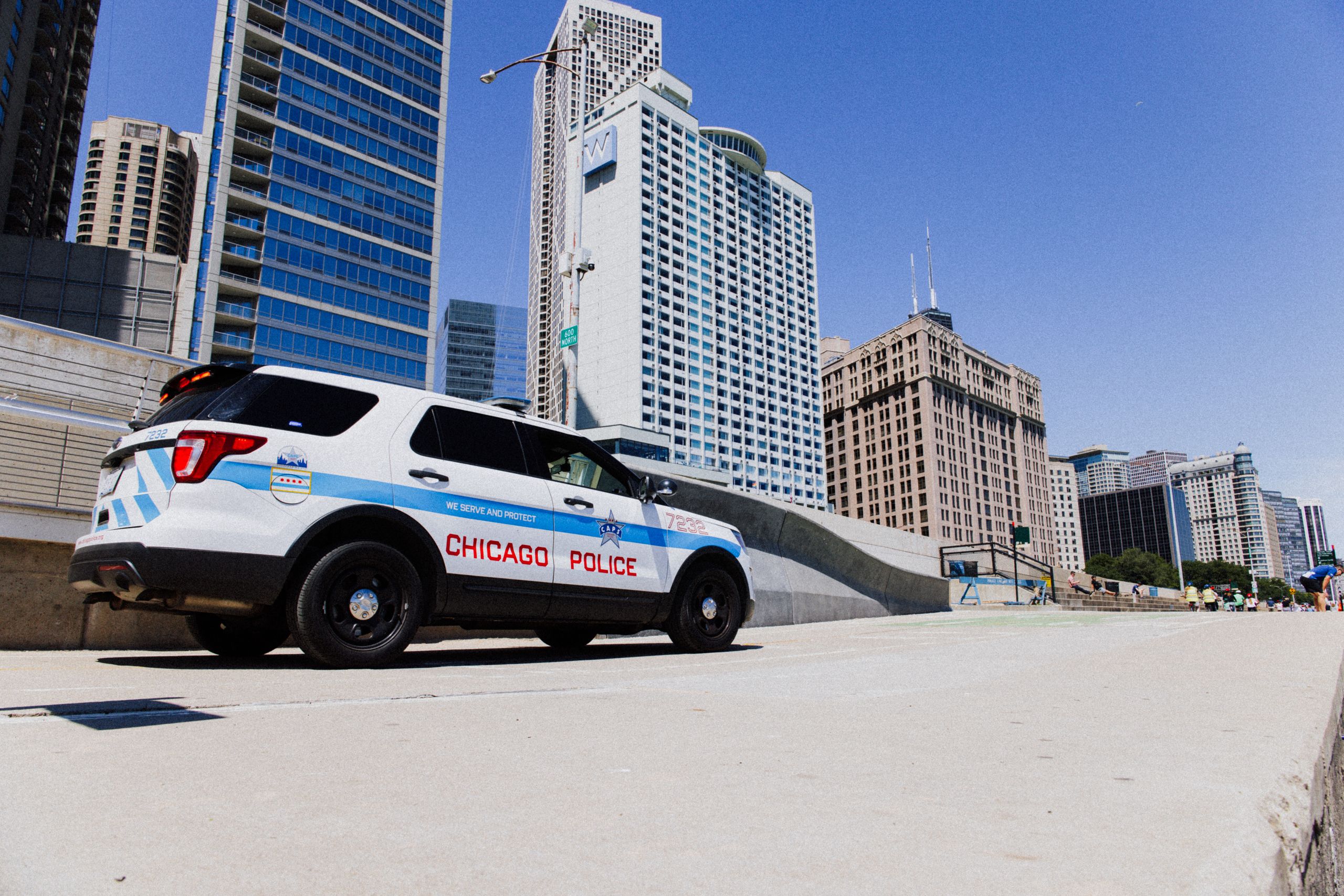 A Chicago Police SUV parked downtown against a skyline backdrop on a clear day.