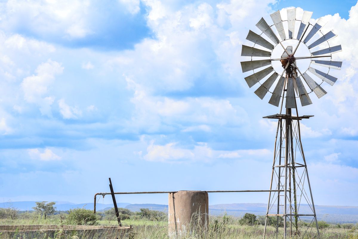 A classic windmill stands against a bright blue sky with scattered clouds, embodying rustic charm and rural tranquility.