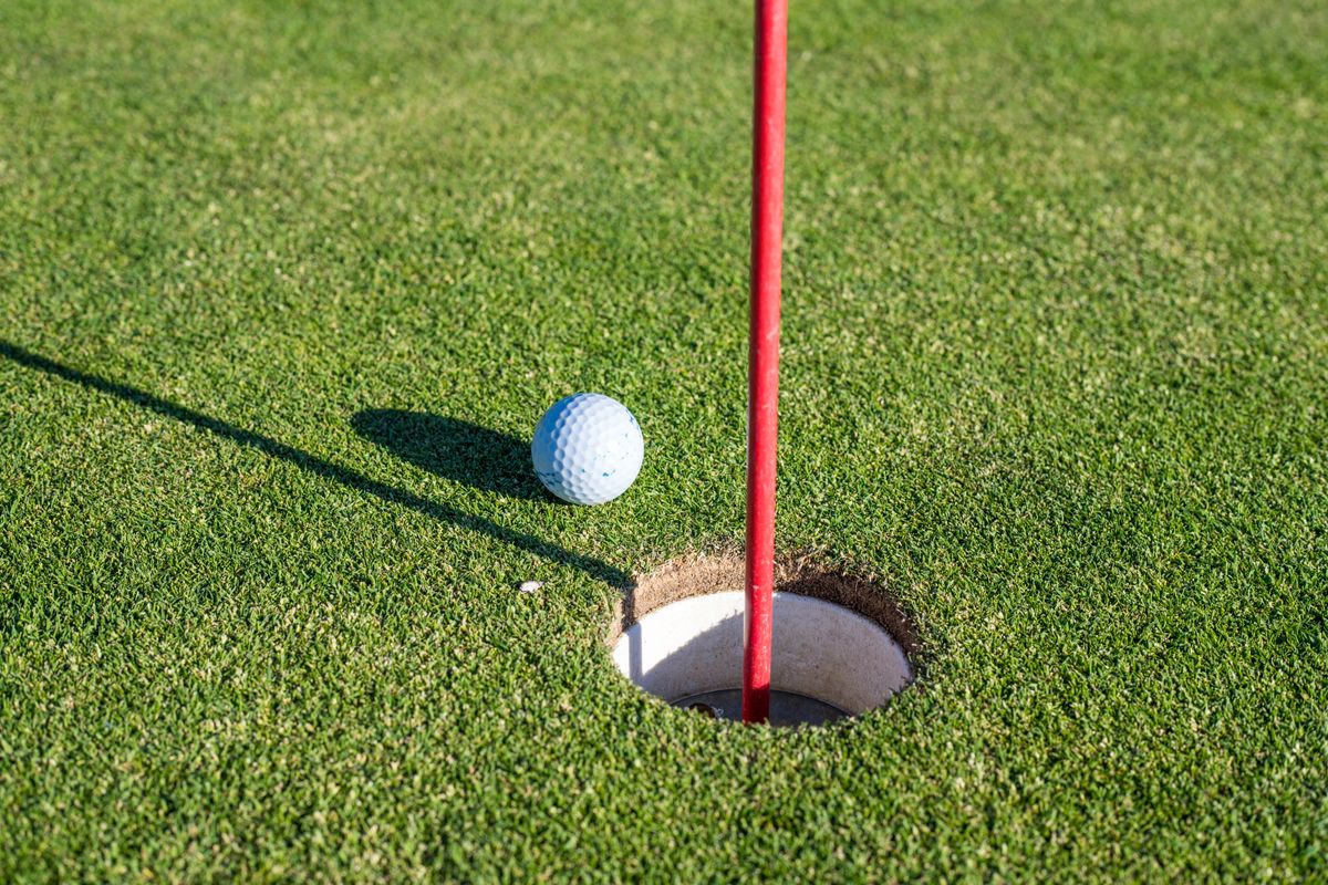 17 Presidential Habits That Made America’s Most Powerful Men Look Surprisingly Odd 2 A close-up of a golf ball near a hole on a green with a red flagpole, symbolizing precision and sport.