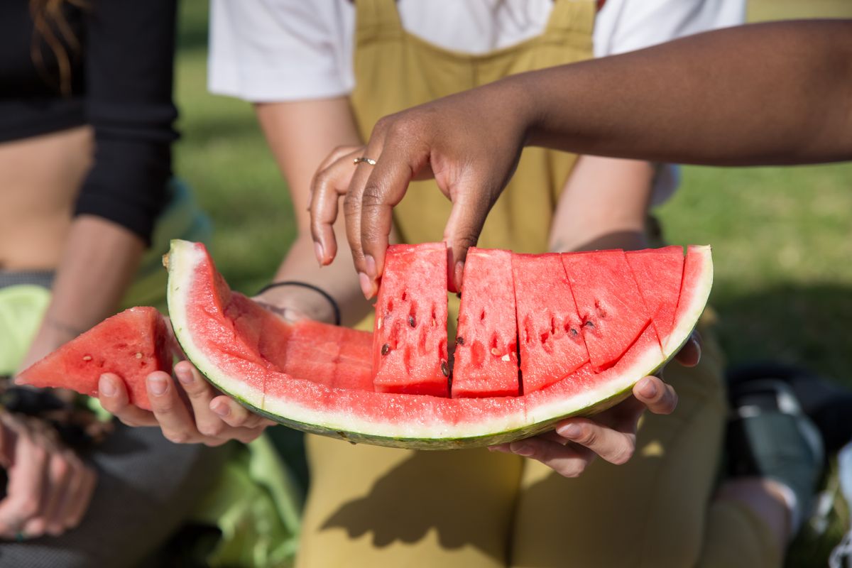 Beware Before You Grab That Watermelon: Shocking Truths Grocery Stores Won’t Tell You 4 A close-up of hands sharing freshly sliced watermelon on a sunny day outdoors.