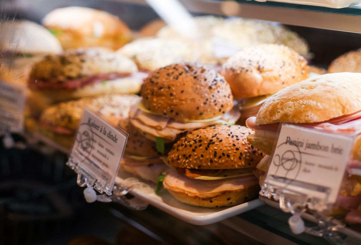 A close-up view of fresh sandwiches with sesame seed buns on display in a Quebec, Canada bakery.