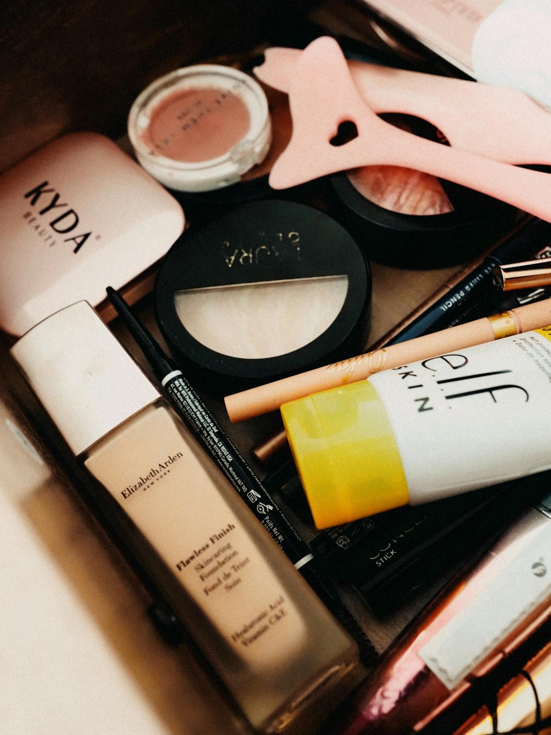 A collection of beauty products including foundation, powder, and skincare items in a drawer.
