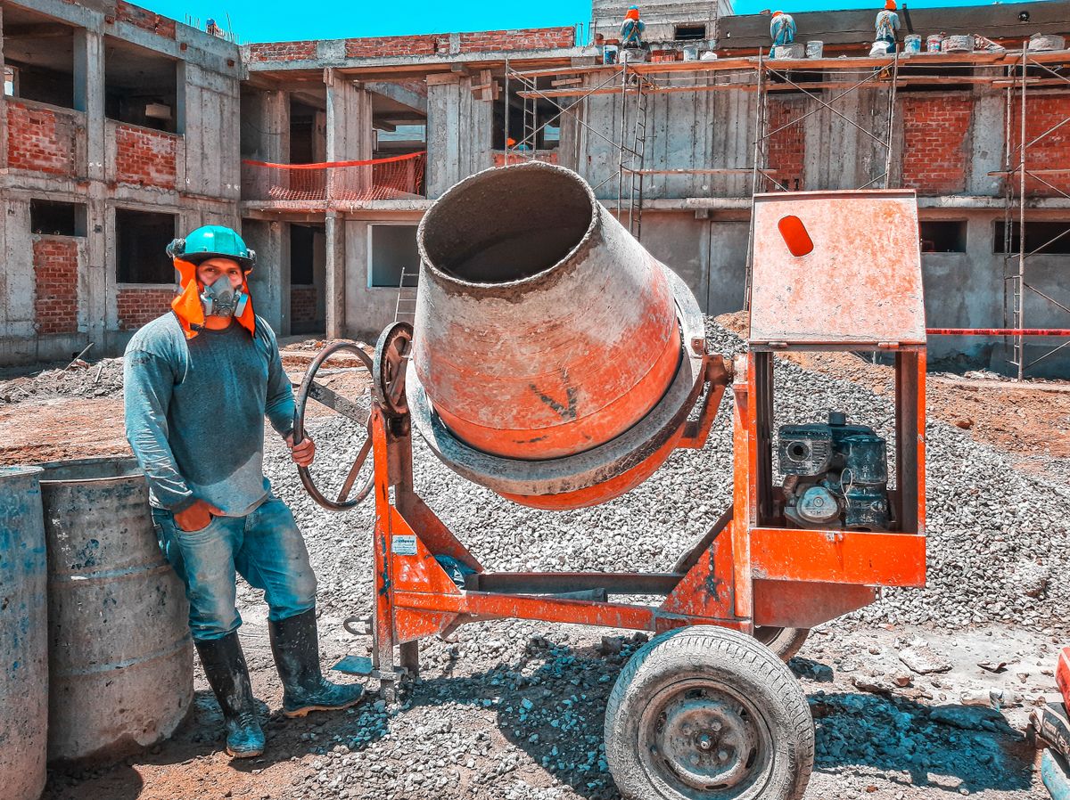 ICE Raids Were Sold As A Jobs Fix, But The Data Tells a Much Darker Story 1 A construction worker operating a concrete mixer at an active building site, emphasizing safety gear.