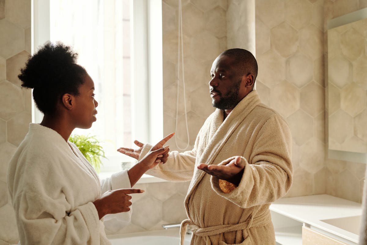 10 Shocking Reasons Good Relationships Fall Apart 3 A couple in bathrobes having a discussion in a bathroom setting, expressing emotions.