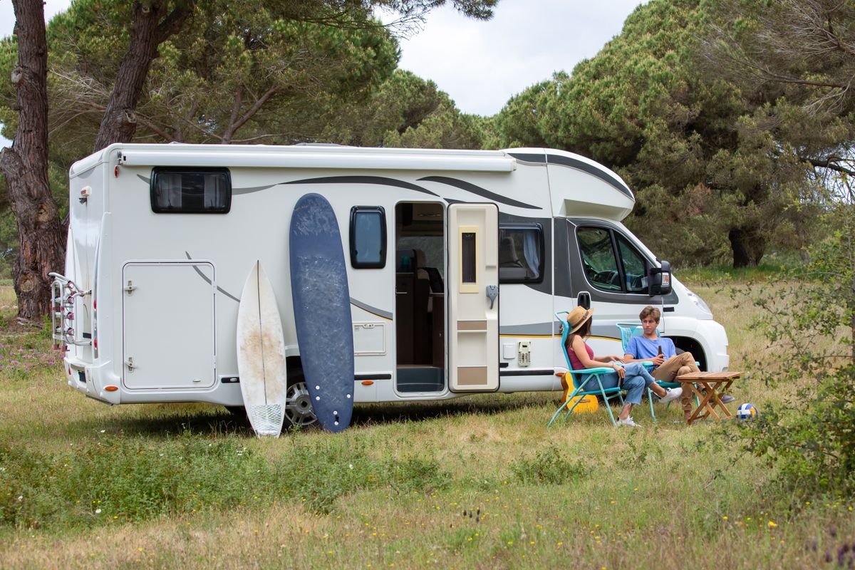 RV Market Collapse and the Trump-Era Energy Shock Behind It 1 A couple relaxes outside their RV with surfboards at a scenic campsite in Portugal, enjoying a summer vacation.