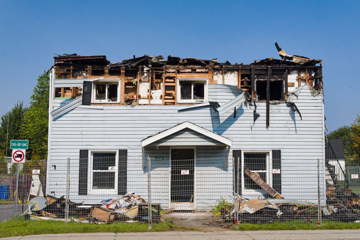 Florida Cities Are Forcing Out the Poor and Elderly Living in RVs in 2026 4 A damaged house with a burnt roof in Bécancour, Quebec, surrounded by a fence.