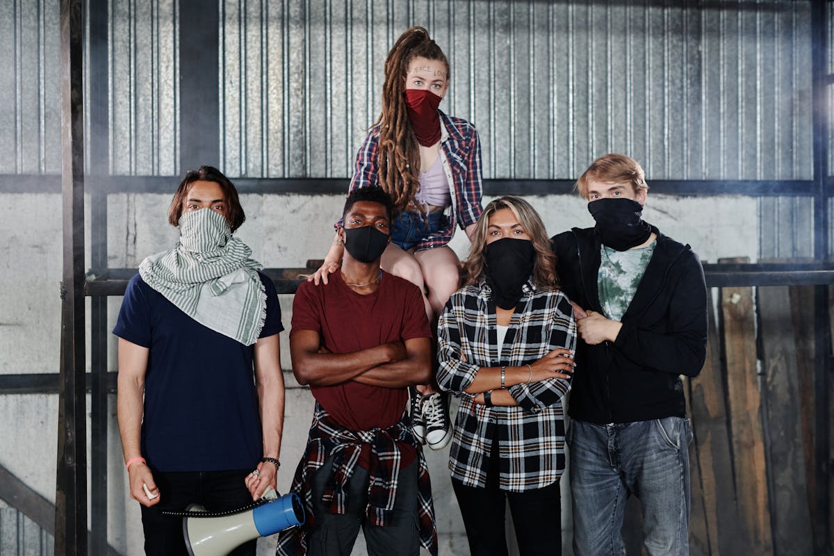 A diverse group of five adults posing indoors with face masks, conveying unity and solidarity.
