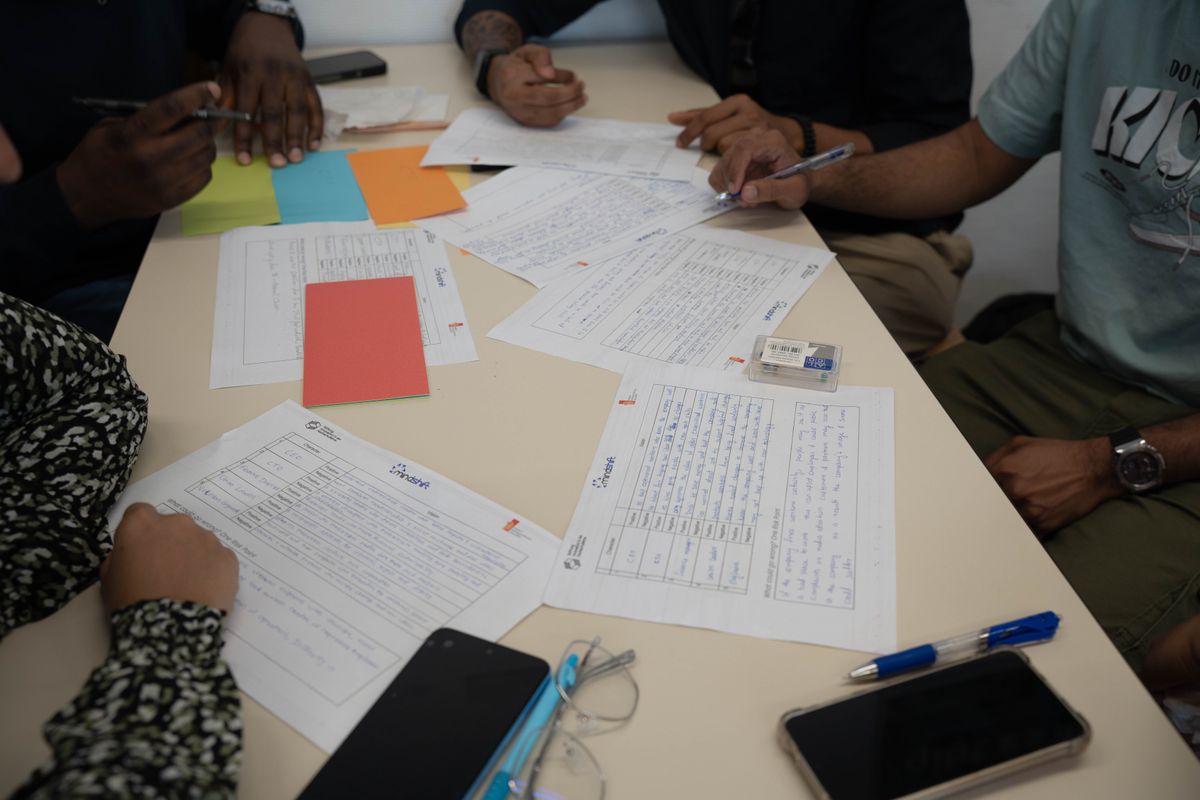 A diverse team working together, reviewing documents and making notes during a collaborative meeting.