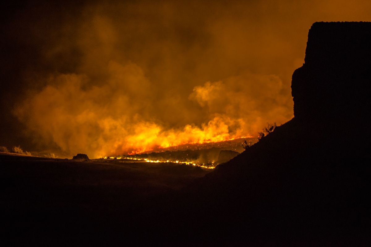 8 California Wildfire Warnings That Should Worry Residents Right Now 1 A dramatic night scene of a forest fire with intense flames and smoke plumes.