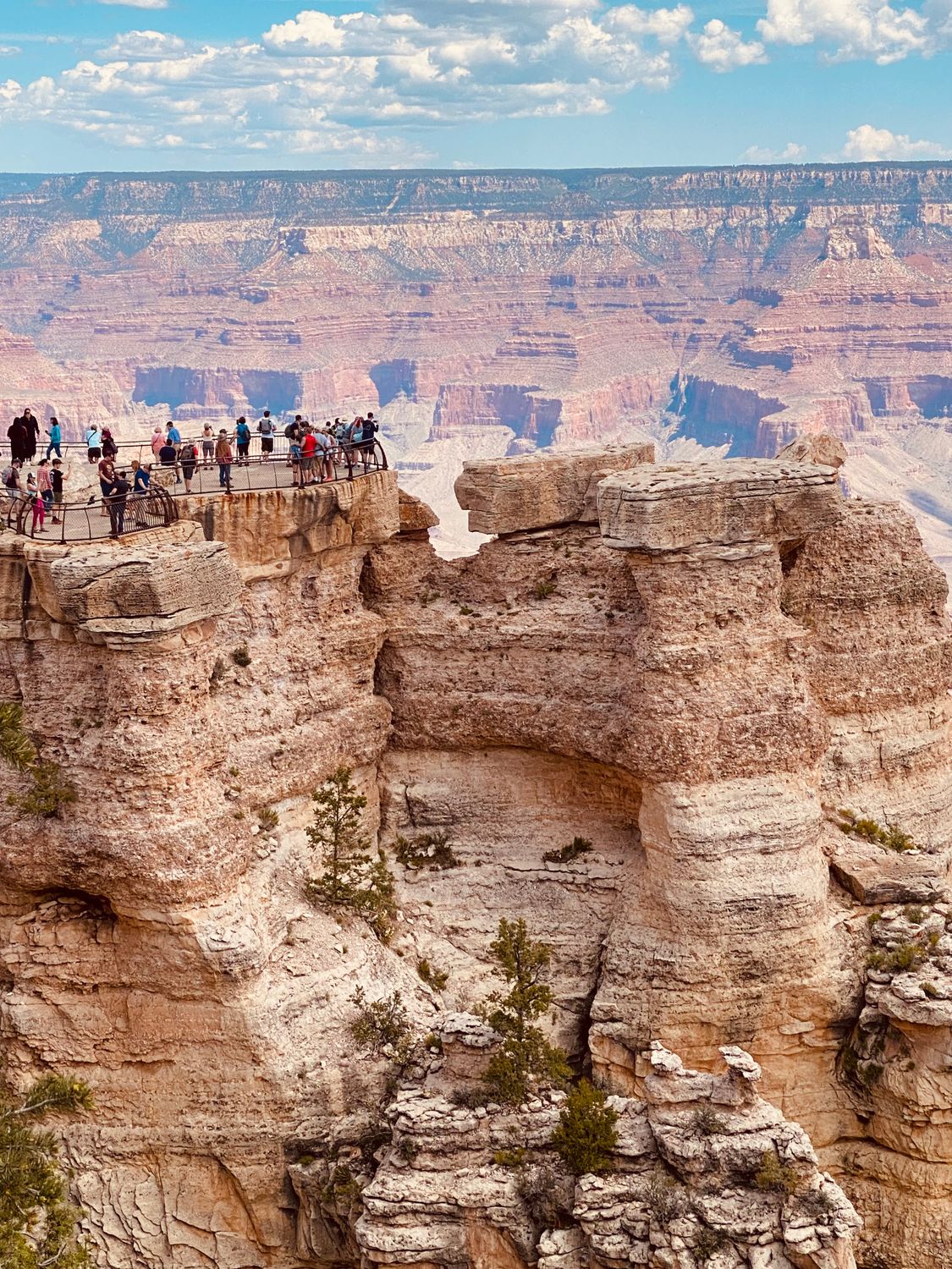 A group of tourists enjoy the stunning view from a Grand Canyon overlook.