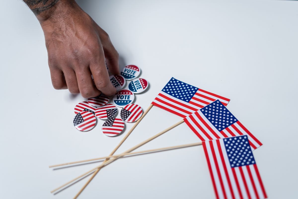 Trump’s Proof-of-Citizenship Voting Rule Hits a Wall as Judge Blocks Election Order 2 A hand reaches for voting buttons and American flags on a white background.