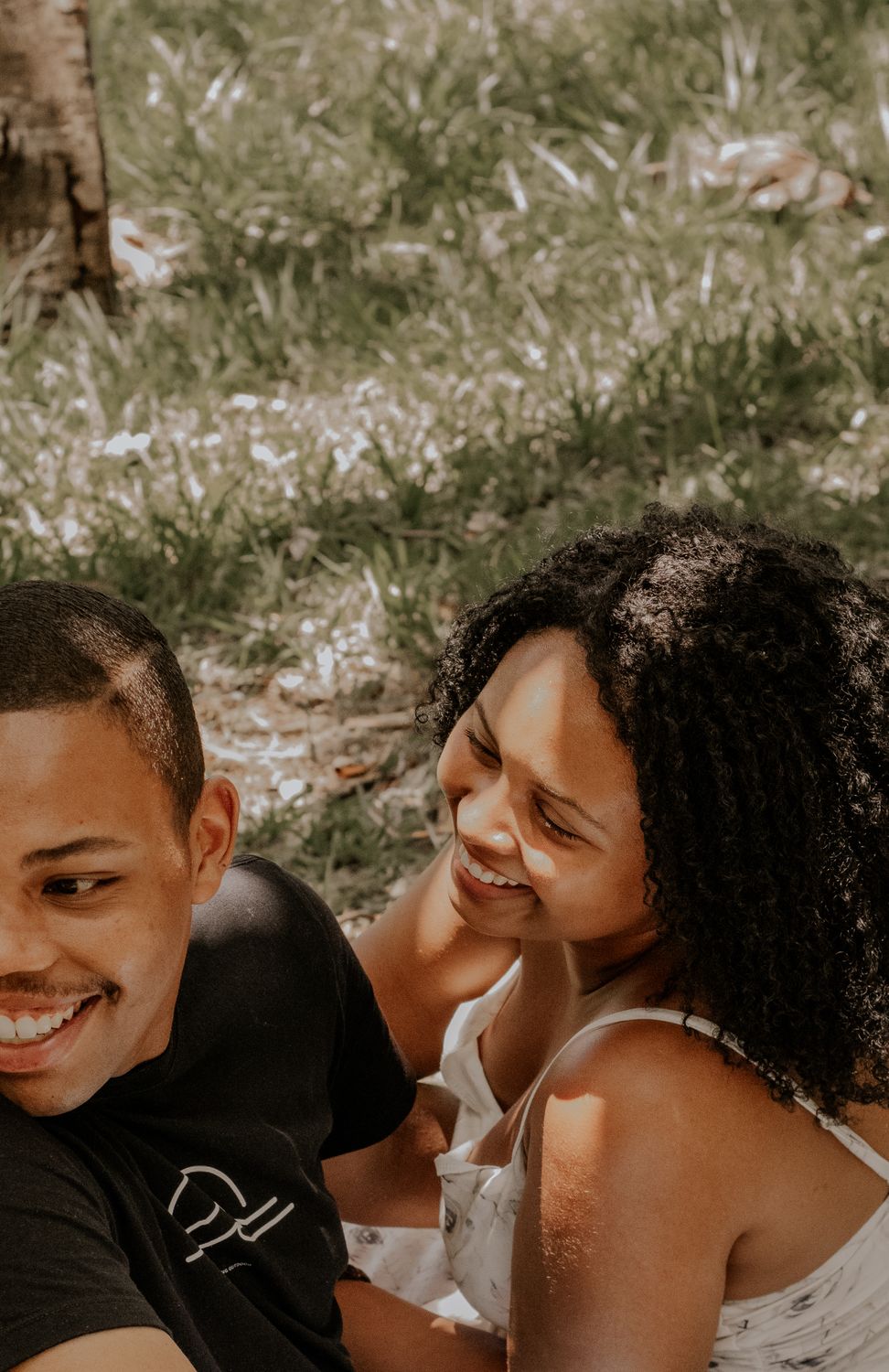 A happy couple enjoying a sunny day outdoors on the grass.
