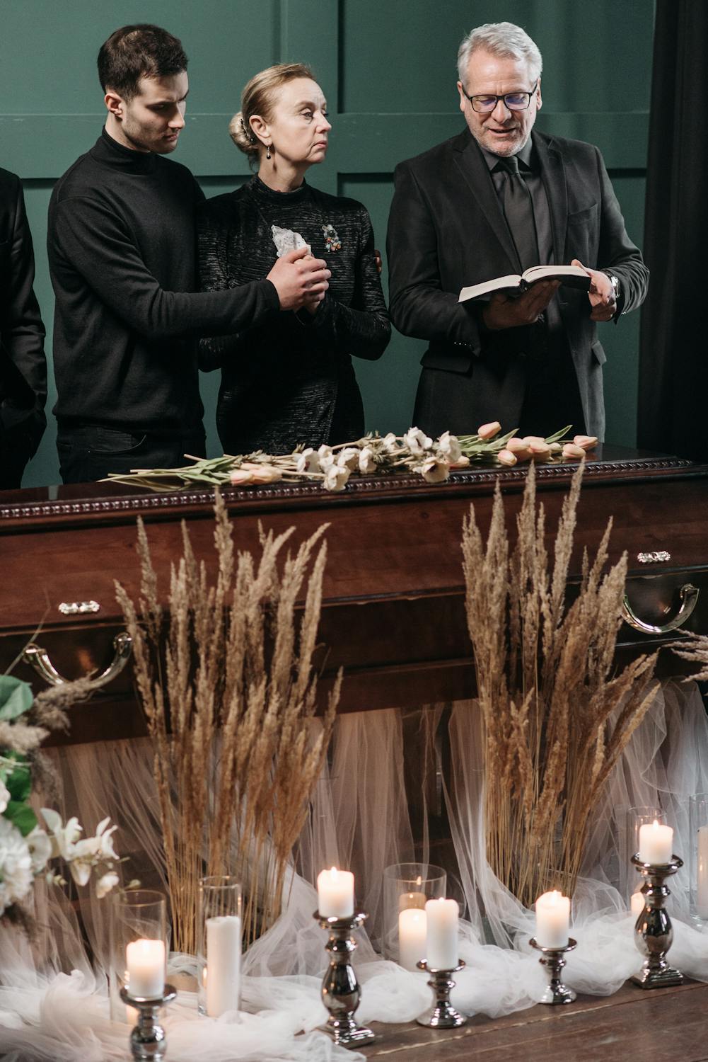 13 Costly Will Mistakes That Can Leave Families Fighting After You’re Gone 3 A heartfelt funeral ceremony with family gathered around a coffin adorned with flowers and lit candles.