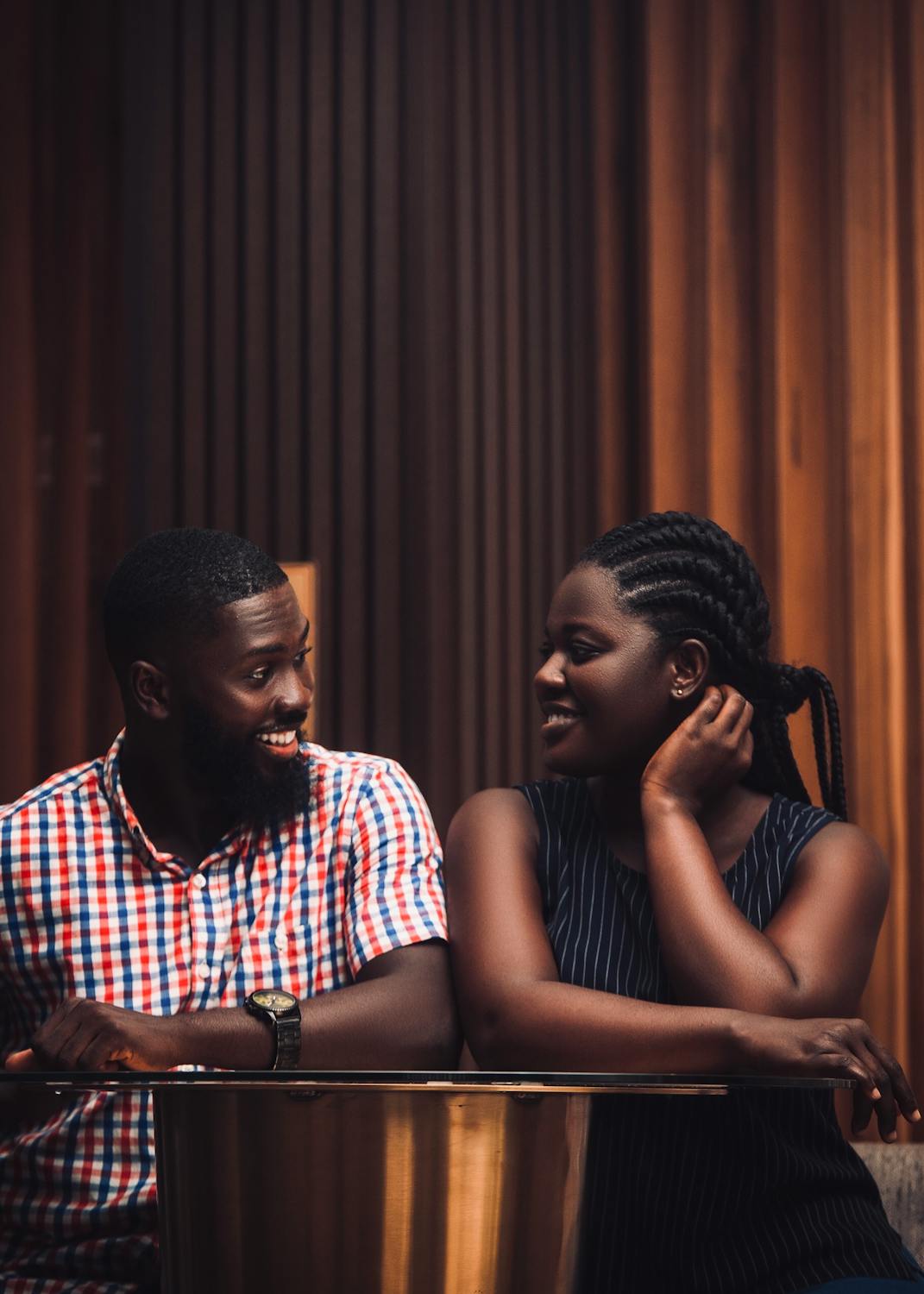 A joyful couple sharing a moment, sitting indoors. Warm and candid.