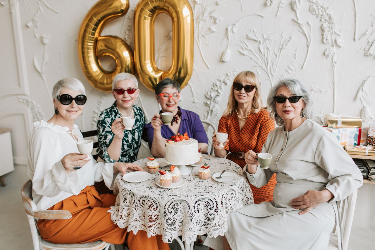 A joyful gathering of senior women celebrating a 60th birthday with tea and cake.
