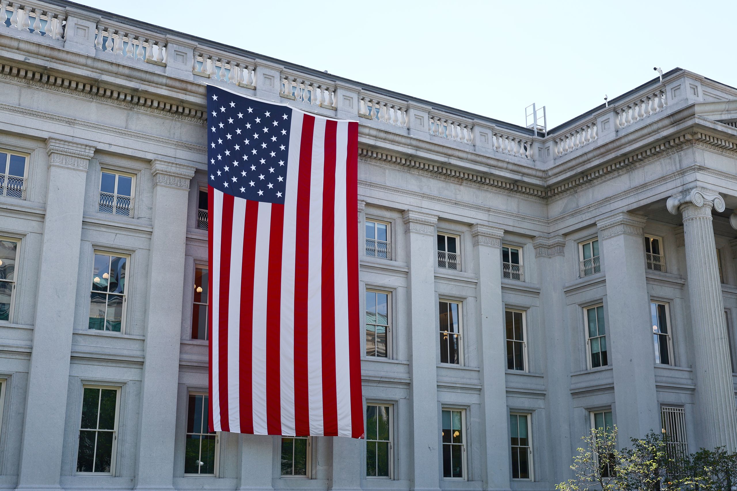 Trump’s Milestone Birthday Sparks Praise, Anger, and One Big Question About the Future 2 A large American flag hangs on a historic government building in Washington, D.C., showcasing national pride.