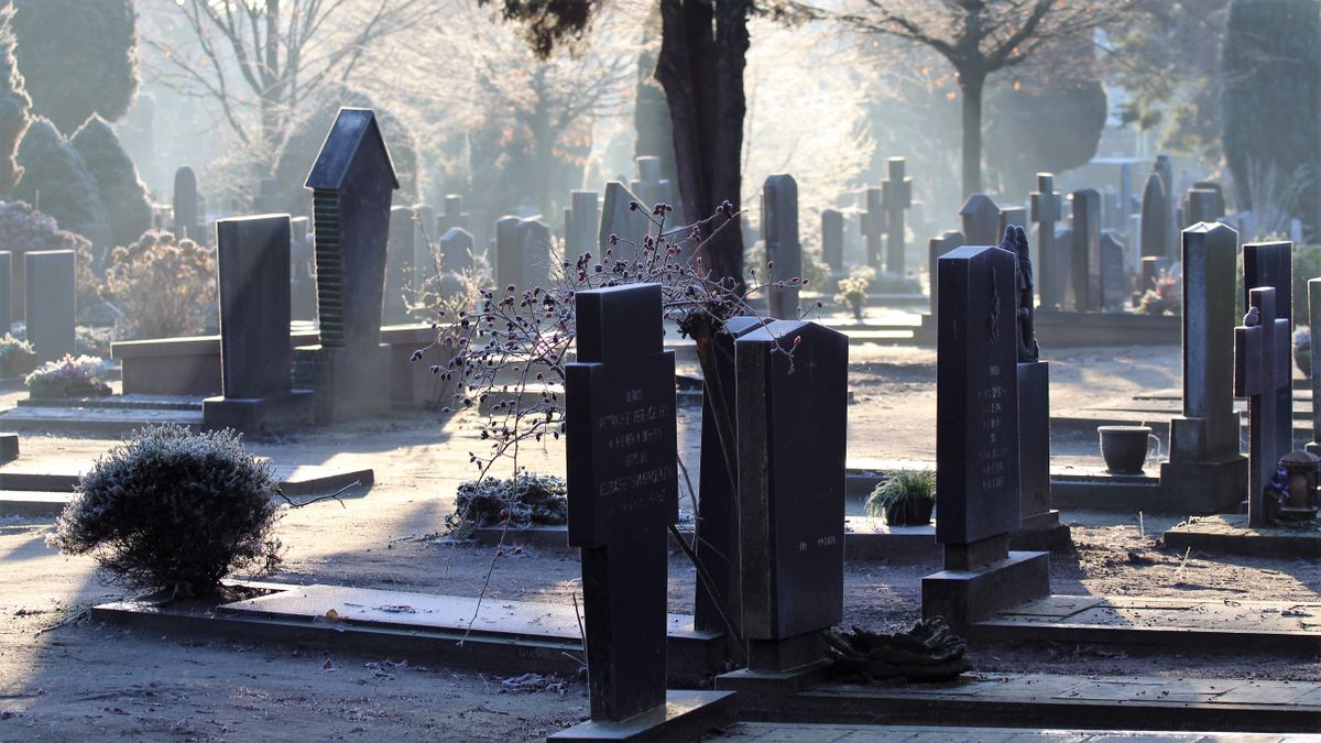 Europe’s Record Heat Has Overwhelmed Paris Mortuaries And Left Families In Distress. 1 A peaceful cemetery scene captured at sunrise, with mist and tombstones creating a tranquil atmosphere.