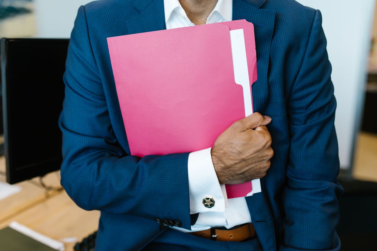 EU Long-Term Residence in Europe: The 5-Year Rule That Could Change Your Future in the EU 3 A professionally dressed man holding a pink folder in an office setting.