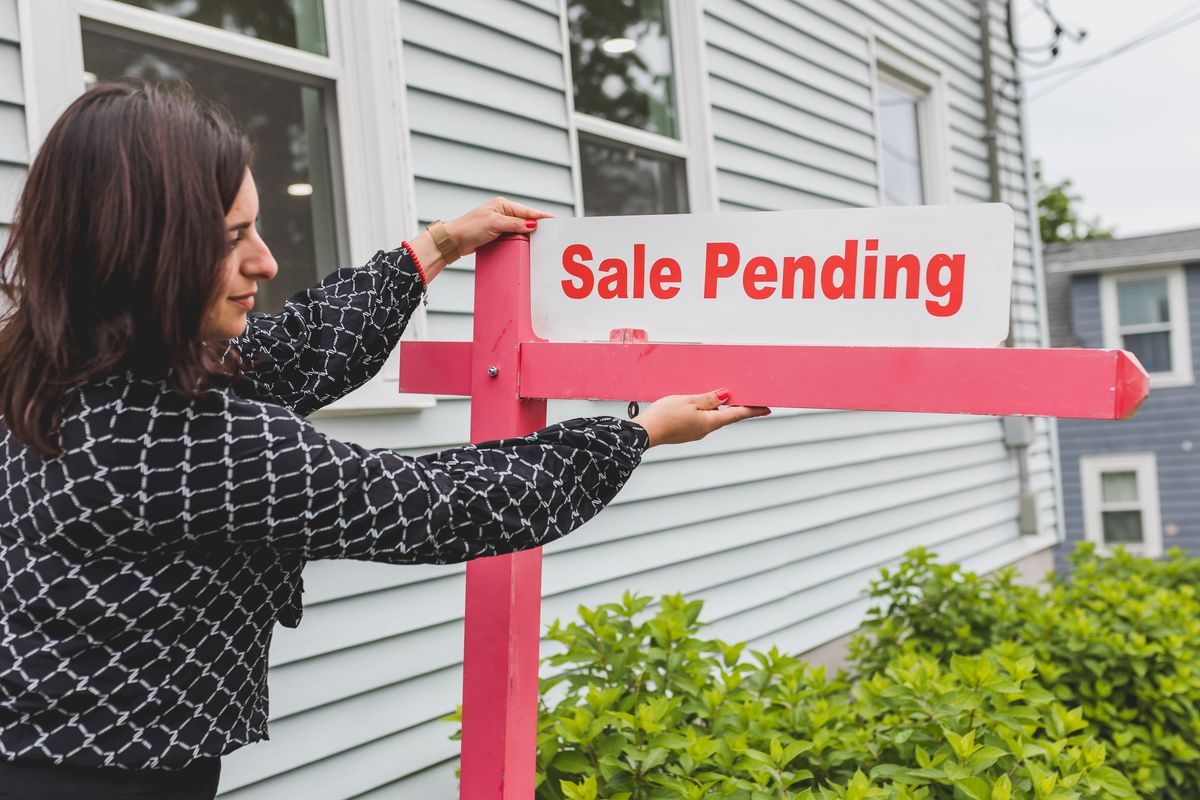 Miami Sellers Are Pulling Homes Off the Market Instead of Cutting Prices, and the Numbers Reveal a Bigger Housing Standoff 1 A realtor adjusting a sale pending sign outside a house for sale.