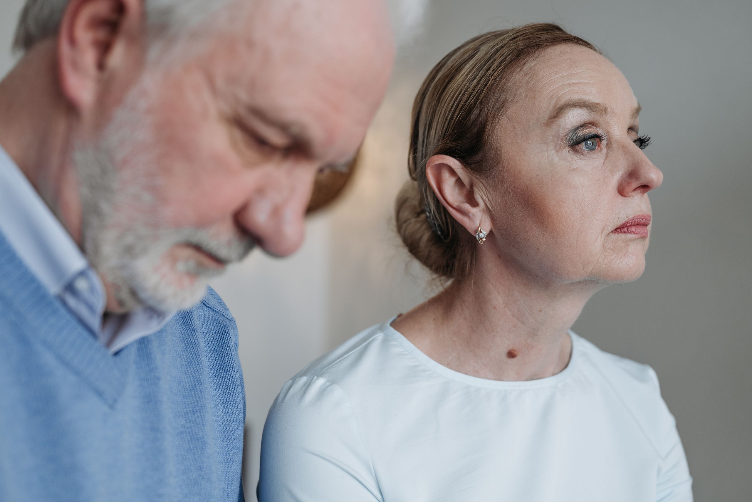 A thoughtful elderly couple captured in a moment of poignant reflection indoors.