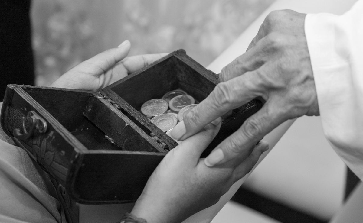 8 Ways In Which Divorce Tears The Family Apart 3 A touching black and white image of hands exchanging coins in a small wooden box, symbolizing trust and tradition.