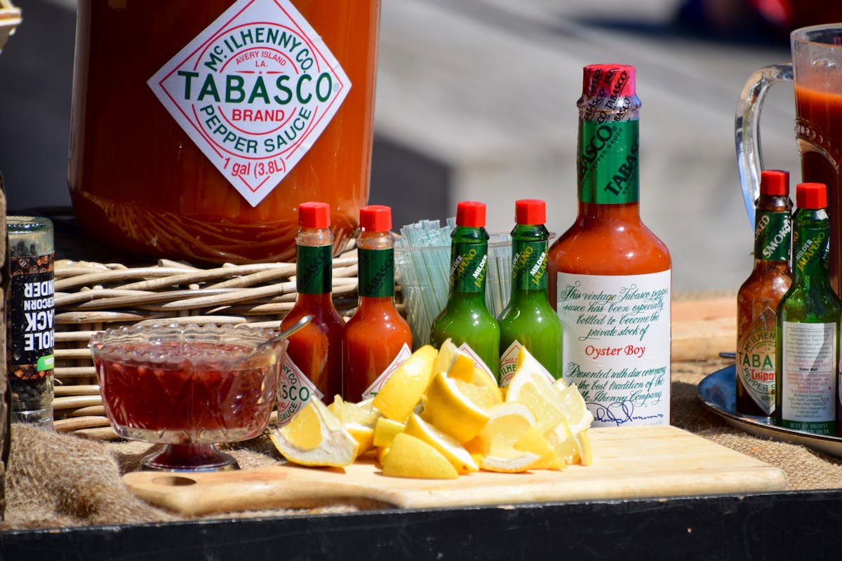 Grocery Prices Are Out Of Control: 10 Items to Grab Before Costs Soar Again 3 A vibrant display of Tabasco sauce bottles, lemon slices, and spices on a wooden board.