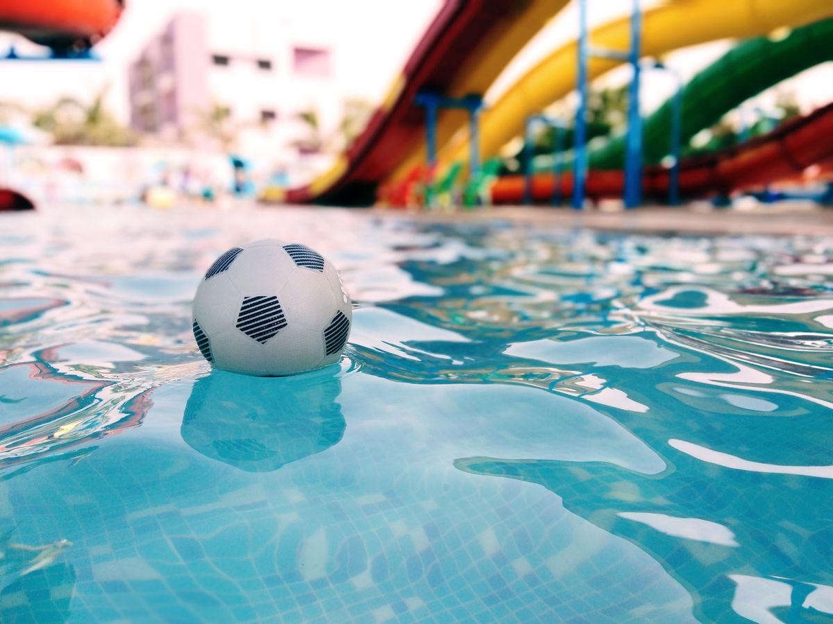 8 Hard Truths Washington Families Should Know Before Wild Waves Closes for Good 4 A vibrant scene at a water park featuring a soccer ball floating in a pool with colorful slides in the background.
