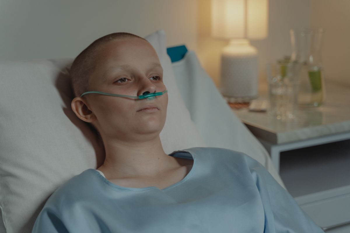 Terrifying Cancer Symptoms People Ignore Until It's Too Late 4 A woman in a hospital bed wearing an oxygen tube, expressing a calm yet serious demeanor.