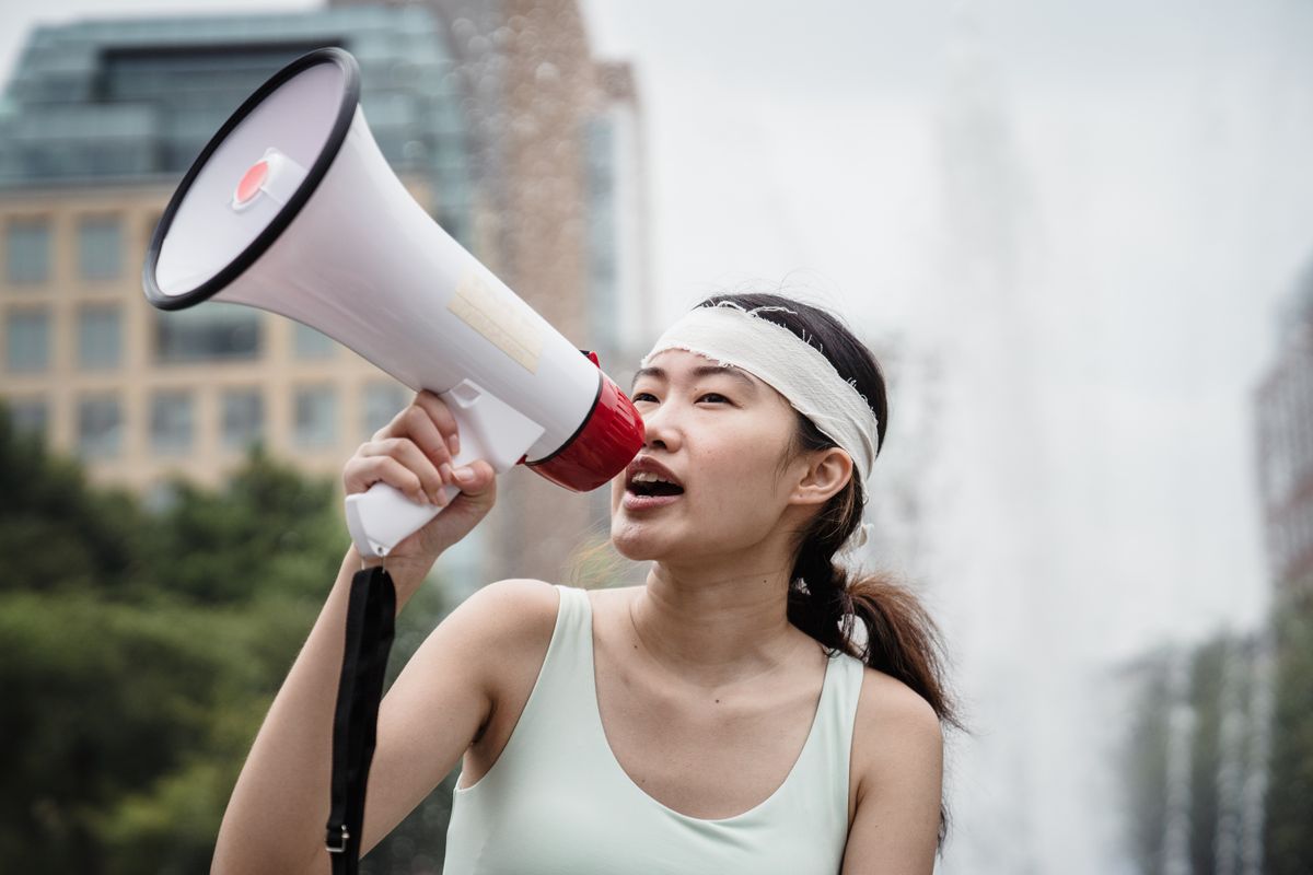A woman passionately speaks into a megaphone during an outdoor protest, emphasizing activism and nonviolence.