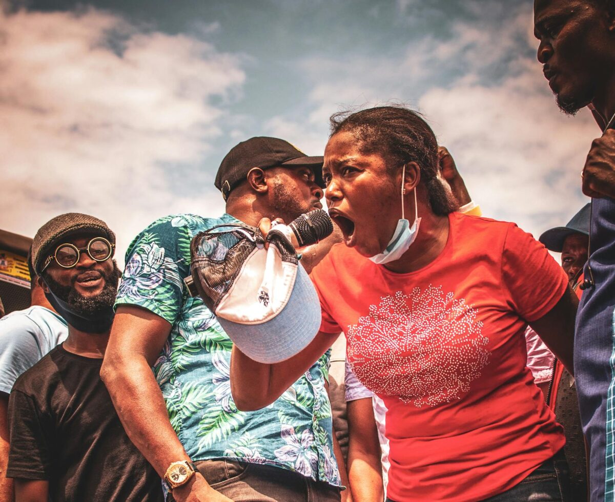 A woman powerfully addressing a crowd with a microphone, exuding energy.