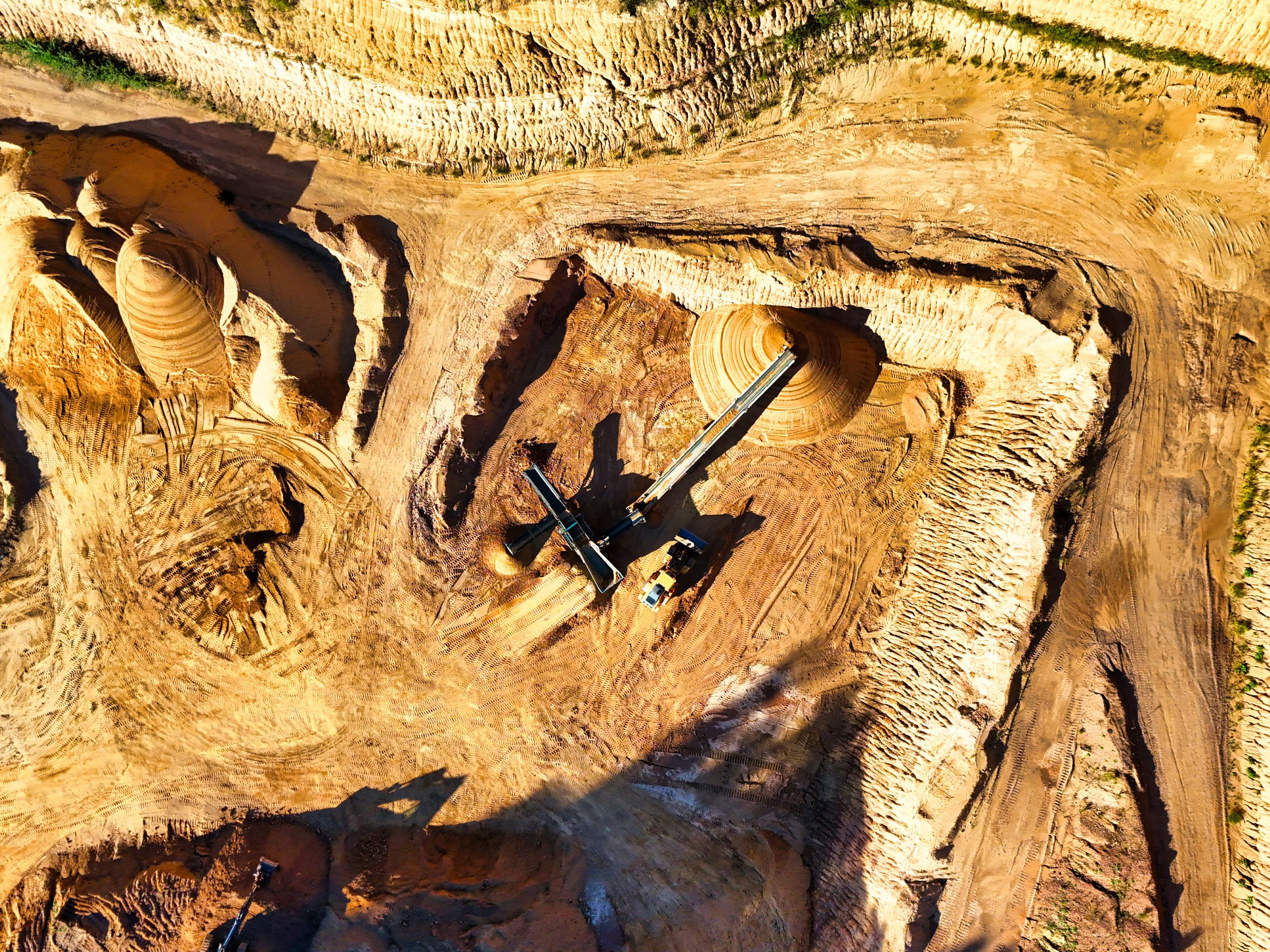 9 Reasons Europe’s Trump-Style Trade Threat Could Blow Up In Its Face 2 Aerial shot of a vast open-pit mine with visible heavy machinery excavating minerals.