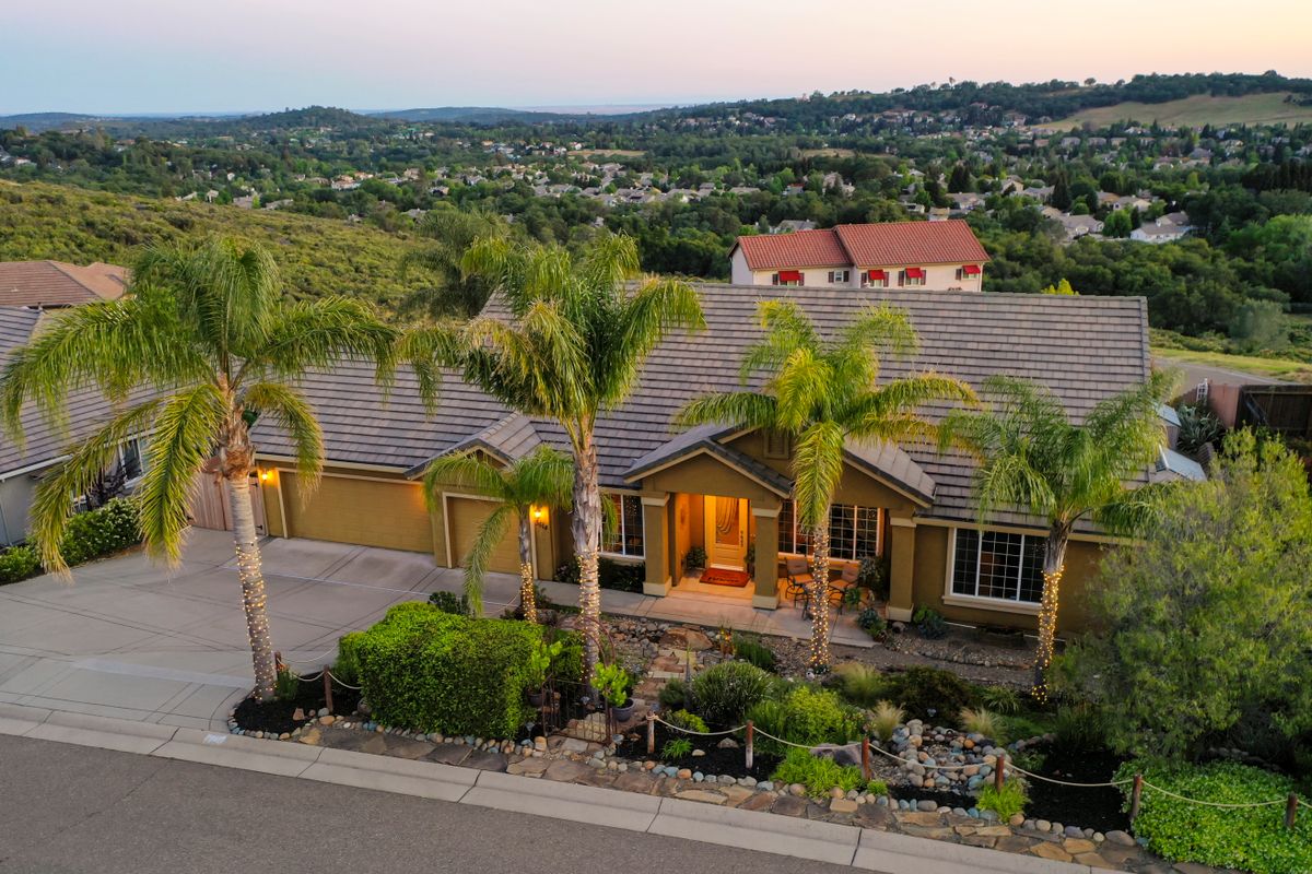 Aerial view of a beautiful suburban home surrounded by lush greenery and palm trees.