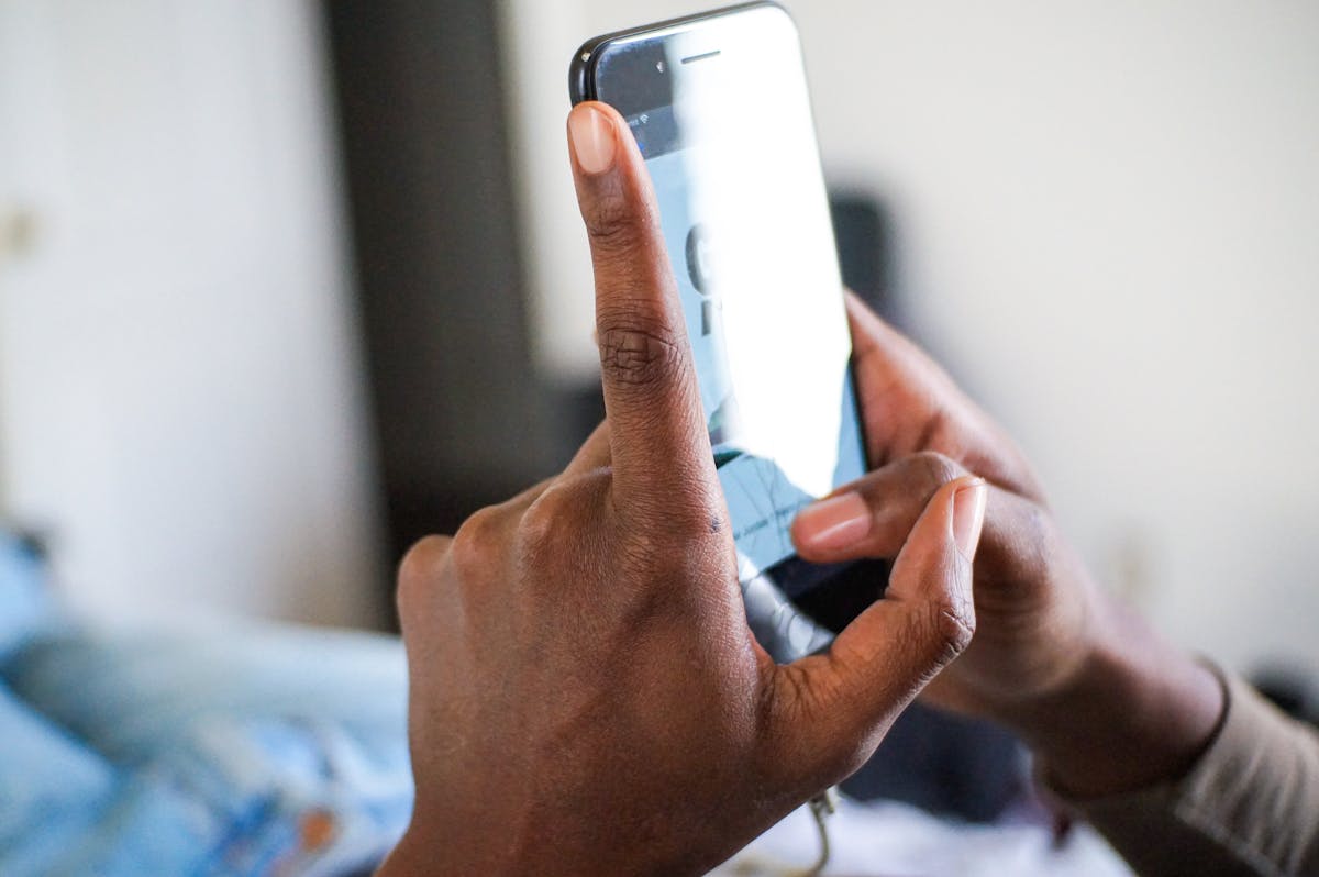 African American hand holding and using a smartphone, focus on texting gesture.