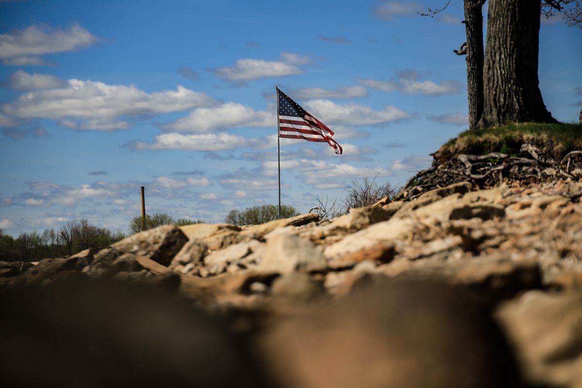 Massachusetts Town Faces Backlash After Warning Homeowners July 4 Flags Could Violate Wildlife Rules 1 American flag waving on a flagpole in a rural landscape with blue sky and clouds.