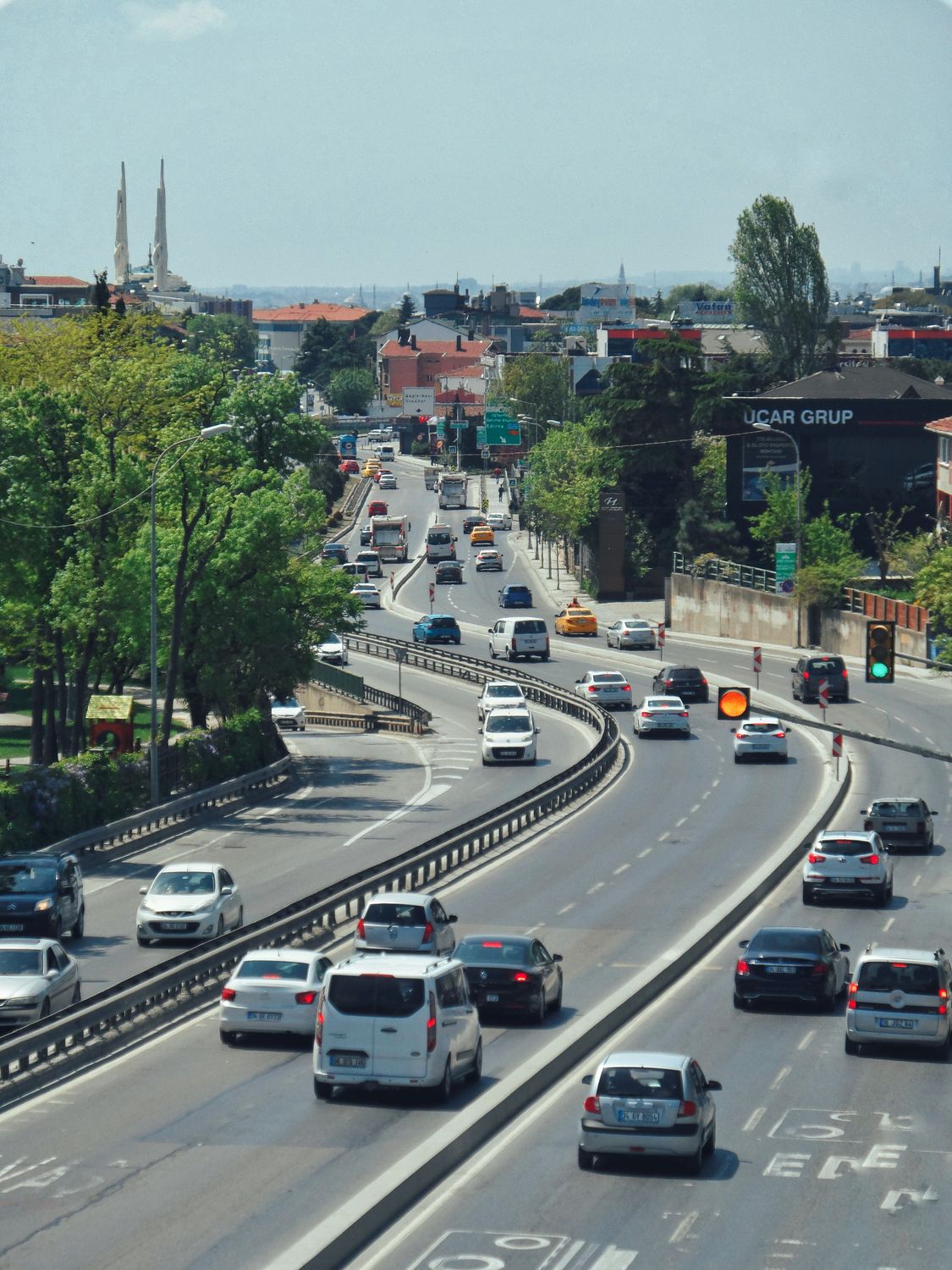 America Is Losing More Than Time in Traffic, and the New INRIX Scorecard Shows How Bad It Has Become 4 An aerial view of a busy city highway with moving cars surrounded by green trees.