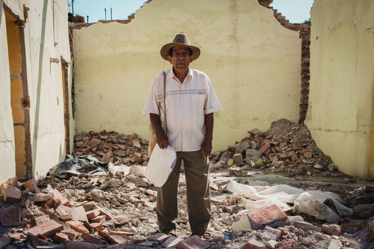 Over 100 Venezuelans Deported From the U.S. Are Missing After Deadly Earthquakes 3 An elderly man stands in debris of a demolished building, showcasing resilience after disaster.