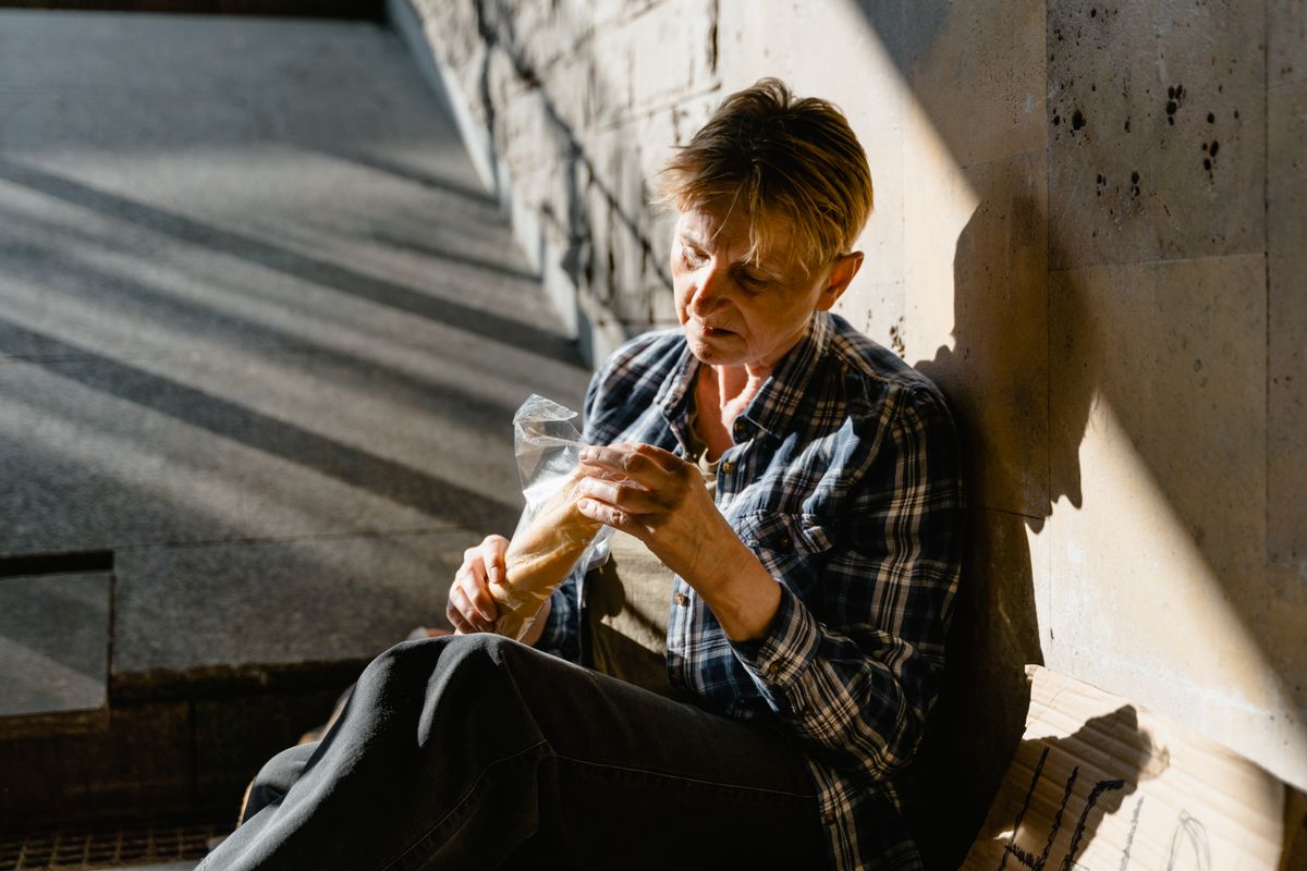 Florida Cities Are Forcing Out the Poor and Elderly Living in RVs in 2026 2 An elderly woman sitting in a sunlit corner, eating, reflecting solitude and resilience.