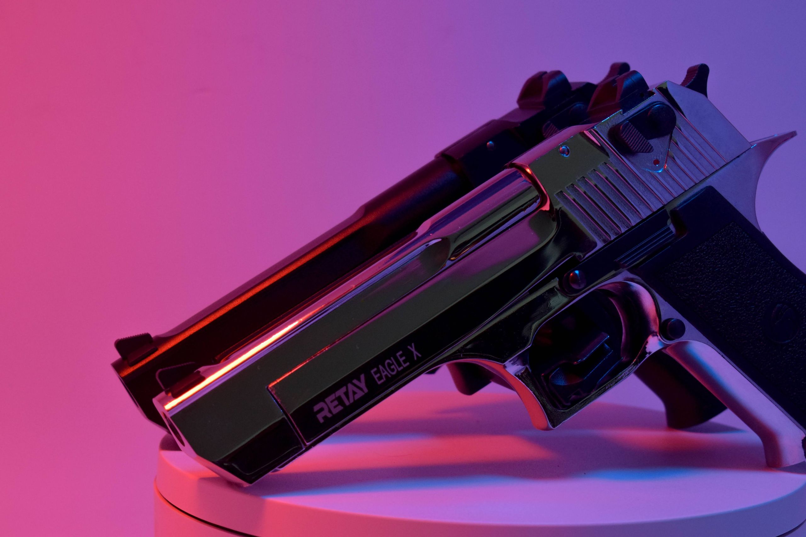 Artistic close-up shot of two handguns under vibrant red and blue lighting, creating a dramatic effect.