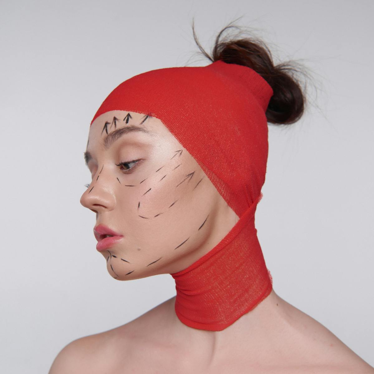 10 Surprising Traits That Can Make You Less Attractive 4 Artistic portrait showing cosmetic surgery markings on model in red wrap.