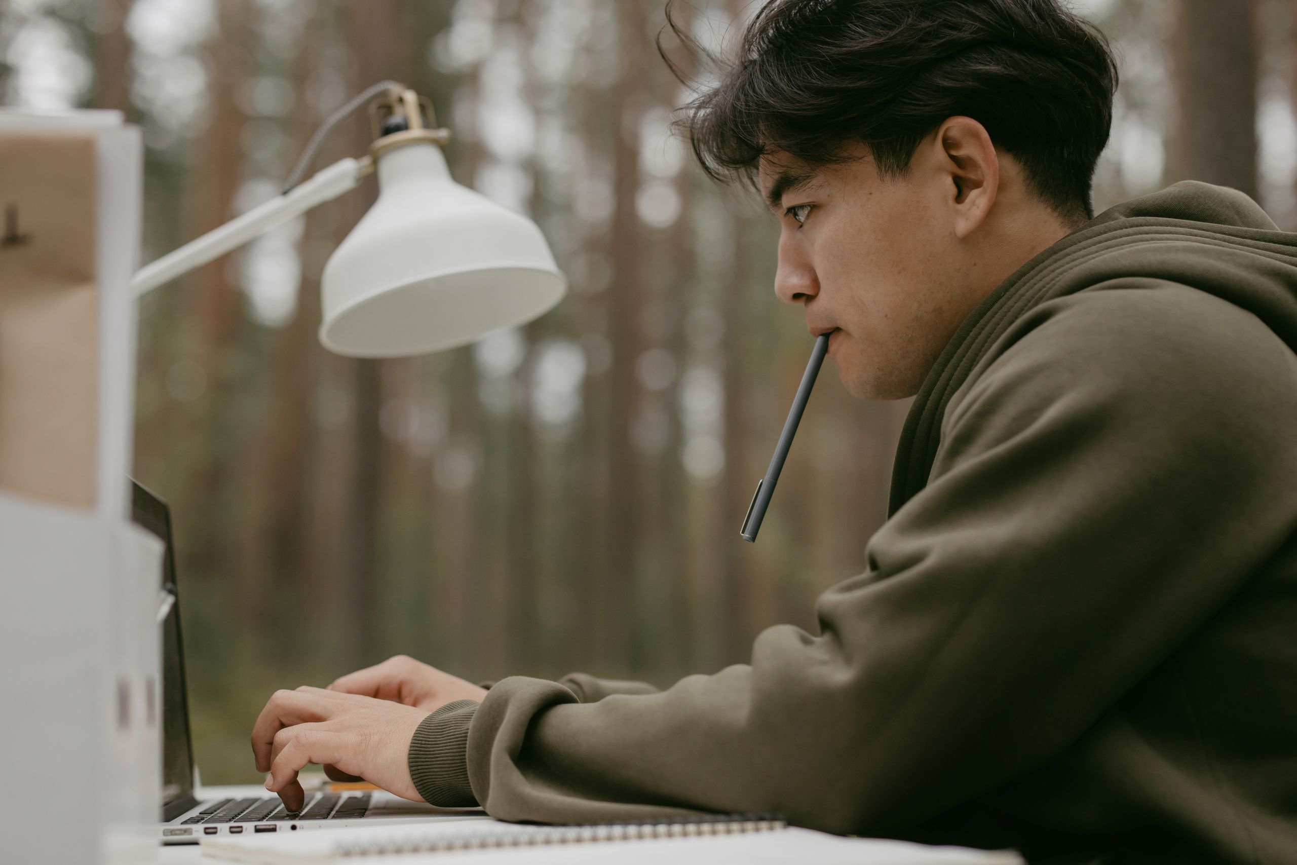 8 Gross Things People Put Near Their Mouth Without Thinking 2 Asian man working intently on a laptop in an outdoor workspace, focused and engaged.