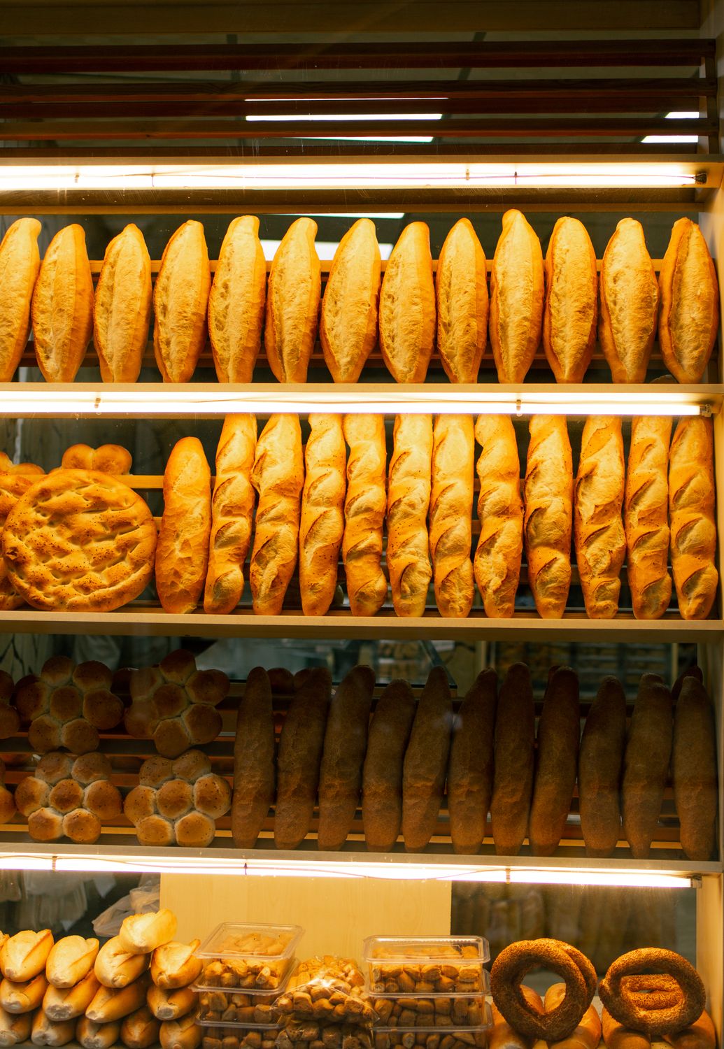Grocery Price Index 2026: Why America’s Food Bills Are Still Rising Even as Weekly Price Growth Cools 3 Assorted fresh bread displayed on wooden shelves in a warm-lit bakery.