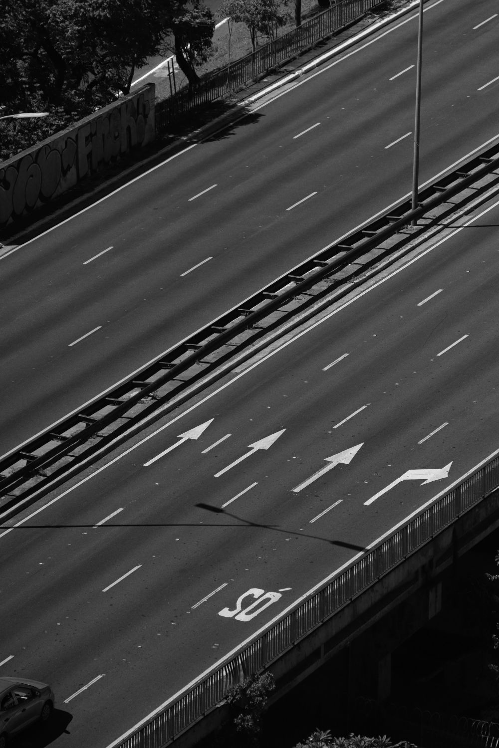 Black and white aerial view of an empty urban highway with directional arrows.