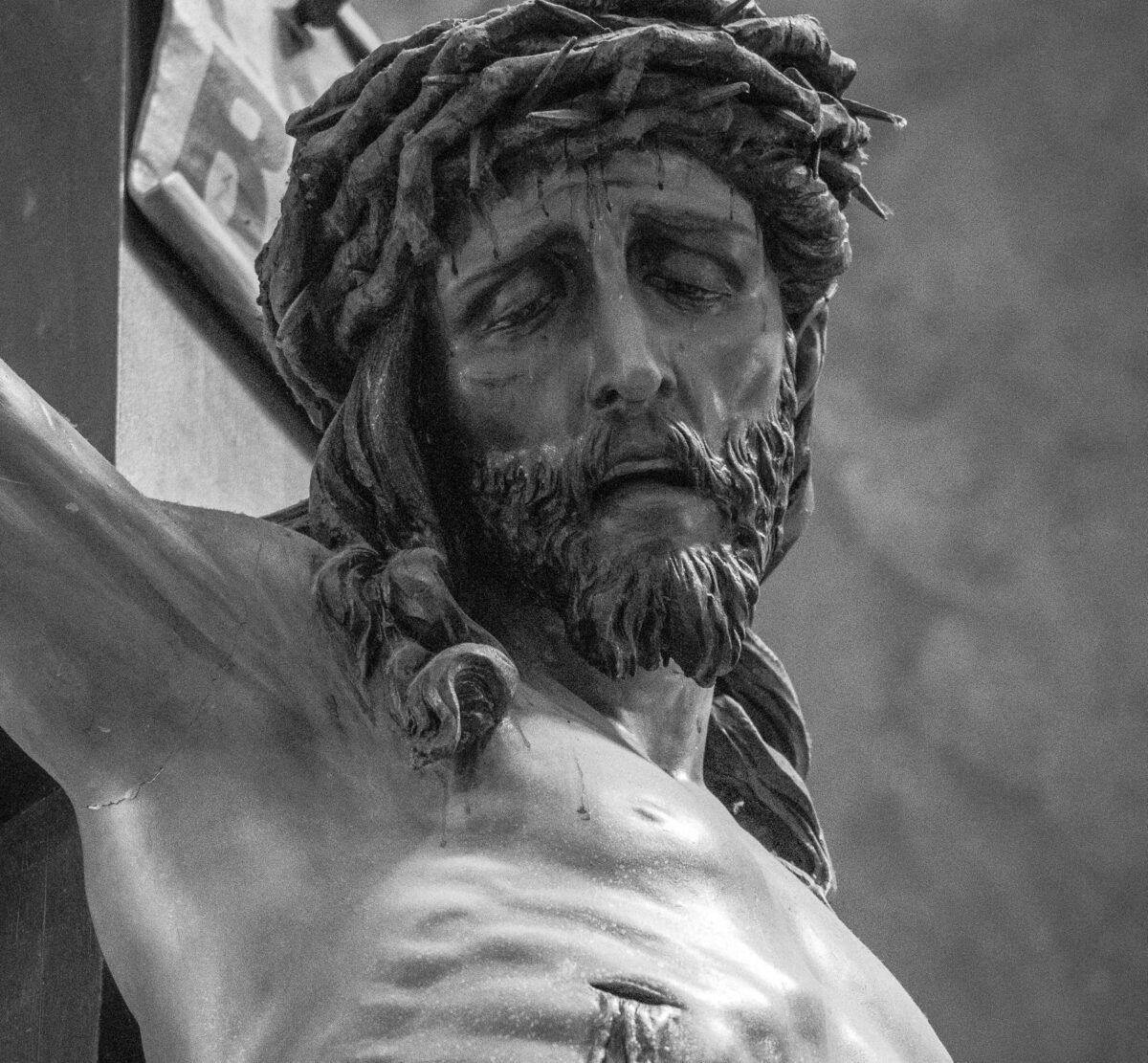 Black and white close-up of a crucifix sculpture conveying religious devotion.