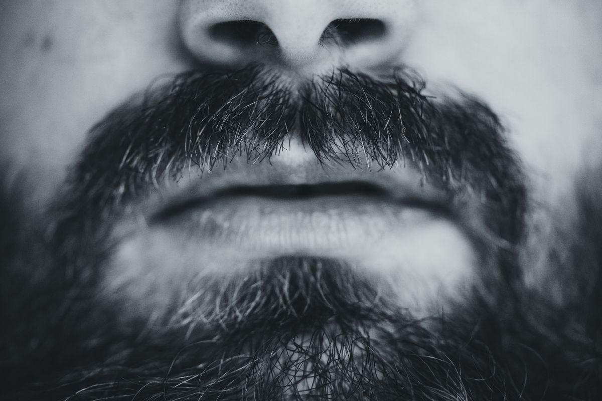 10 Surprising Traits That Can Make You Less Attractive 2 Black and white close-up of a man's bearded face focusing on lips and facial hair.