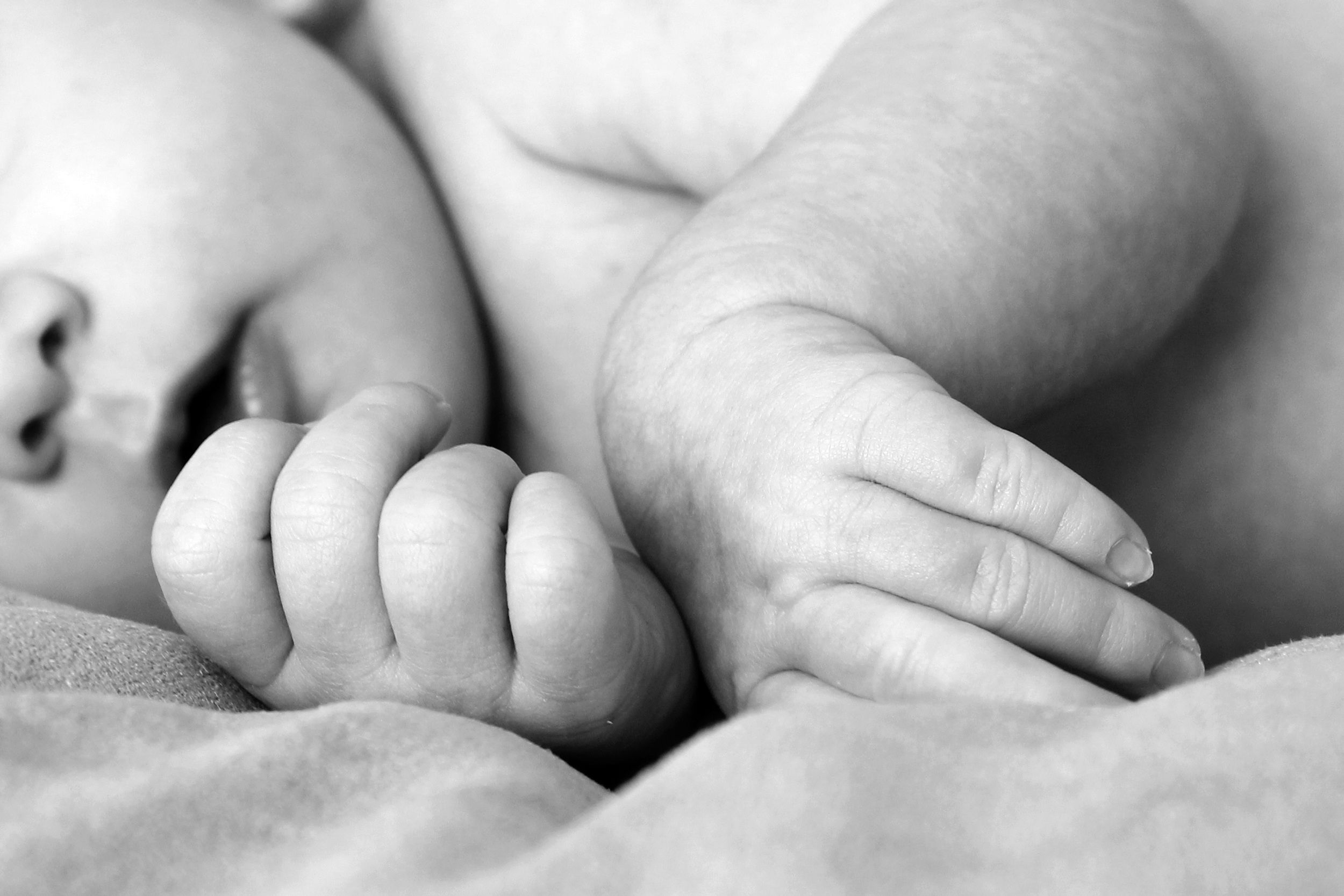 He Mixed Up His Triplets as Babies, and His Family Still Doesn’t Know 1 Black and white close-up of a newborn baby's hands, symbolizing innocence and new life.