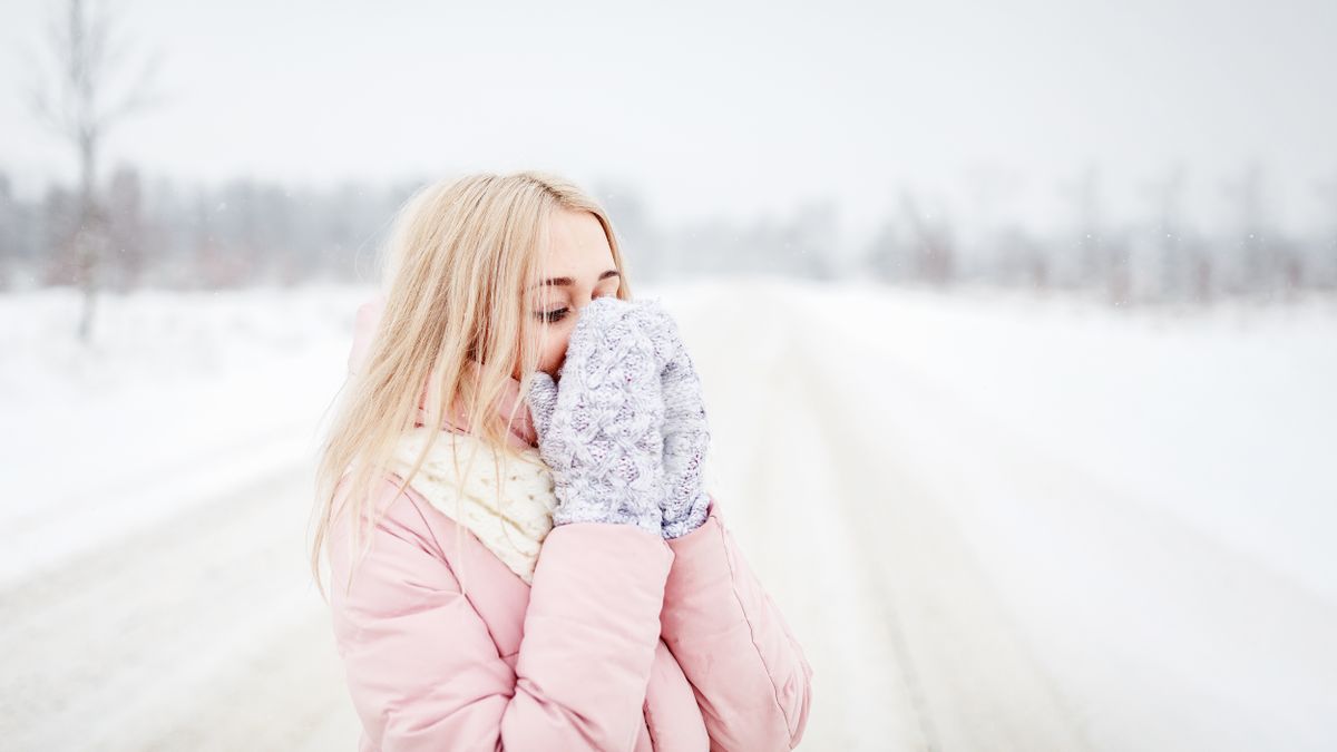 10 Harshest Places People Call Home 3 Blonde woman in pink coat with mittens enjoys the winter snow outdoors.