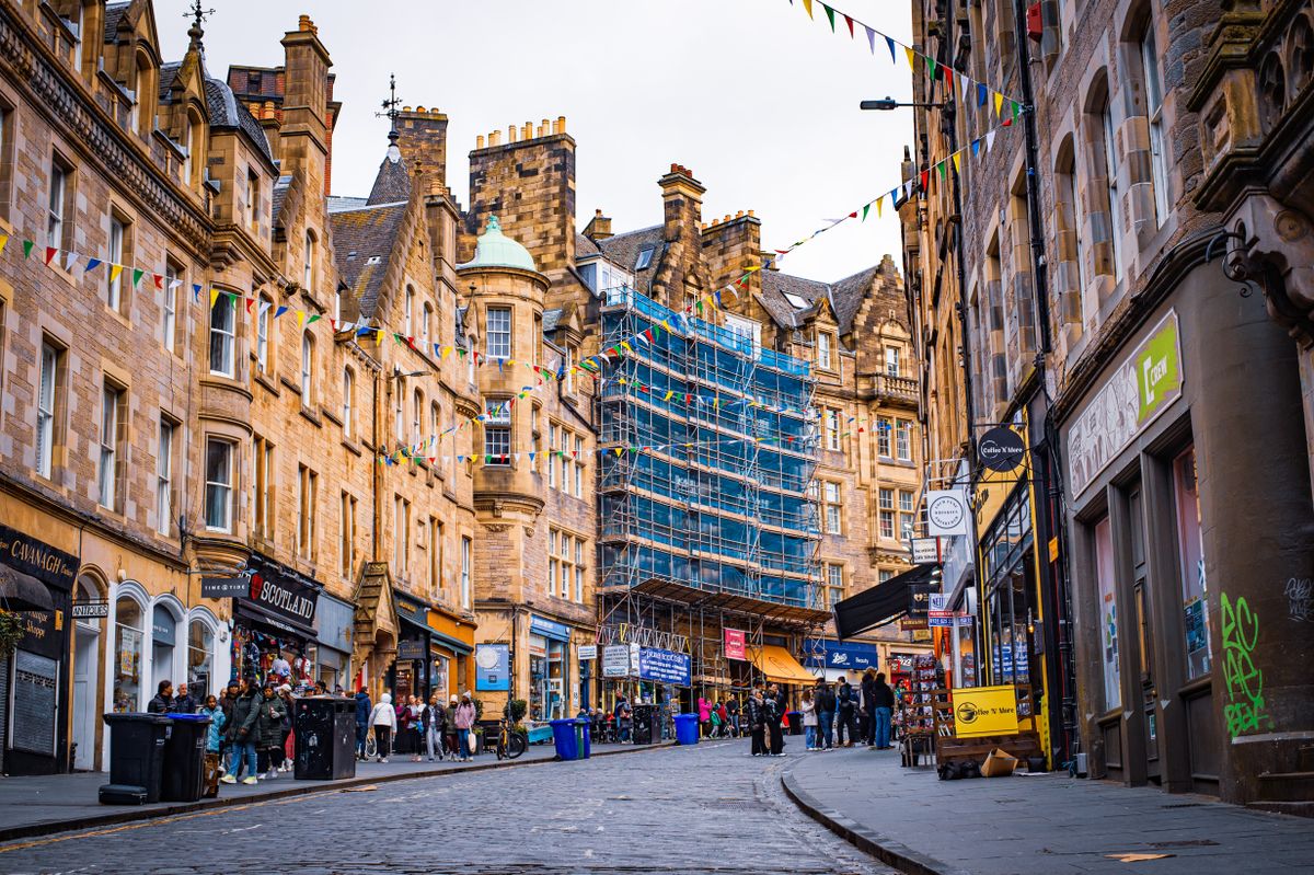 Bustling street scene in Edinburgh with historic architecture and colorful pennant flags.