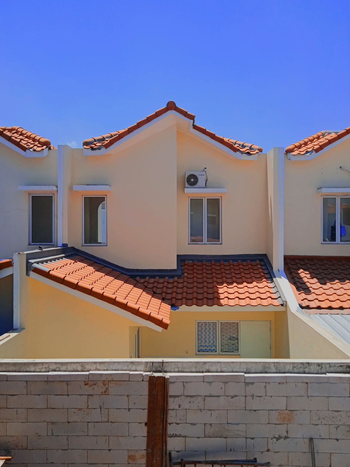 Charming row of townhouses with terracotta roofs and clear blue sky, showcasing suburban architecture.