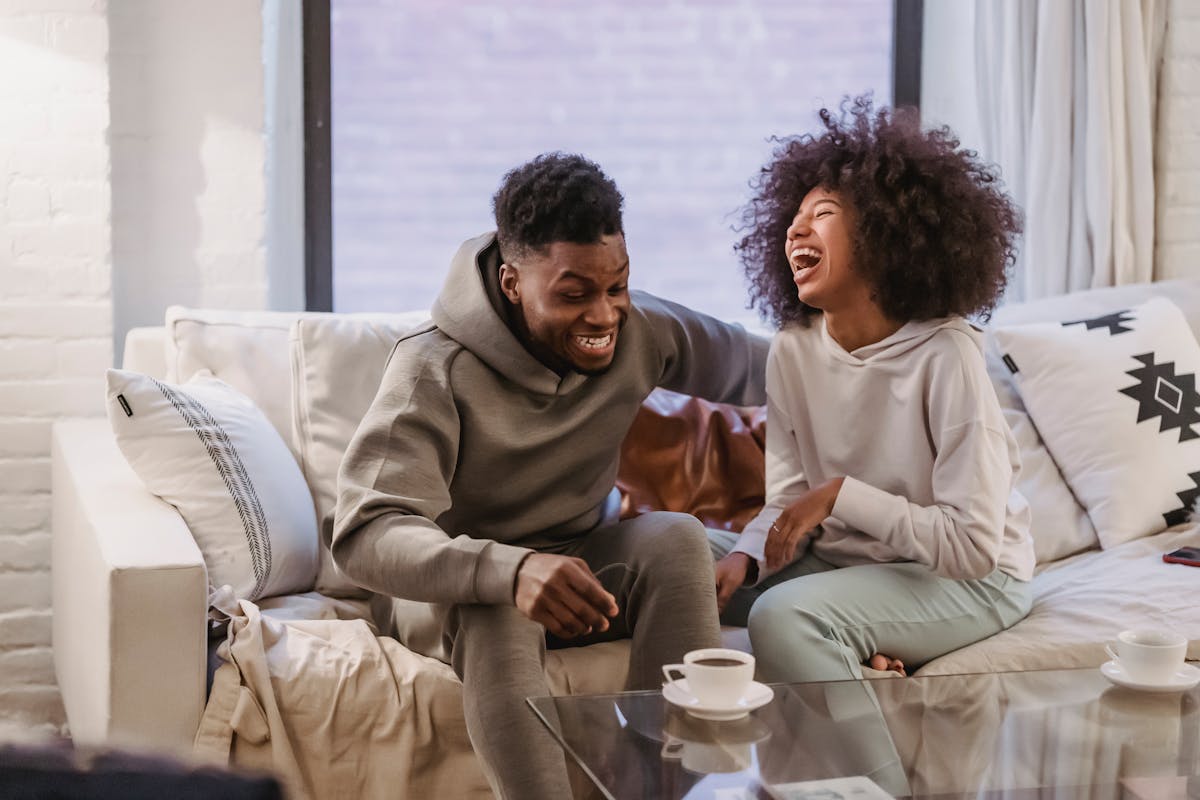 7 Painful Signs You’re More Like A Responsibility Than A Partner To Him 4 Cheerful young African American couple in casual outfit laughing happily while resting together on comfortable sofa at home