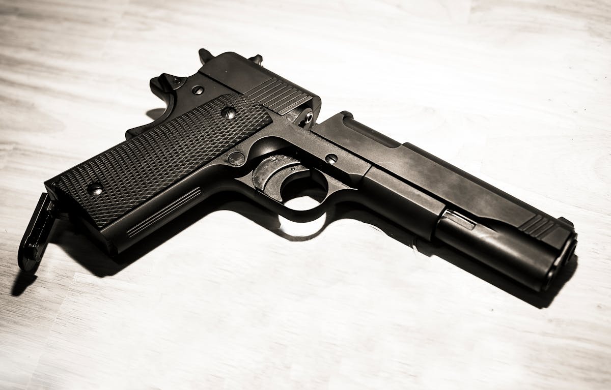 Close-up of a black metal handgun on a light surface, showcasing firearm details.
